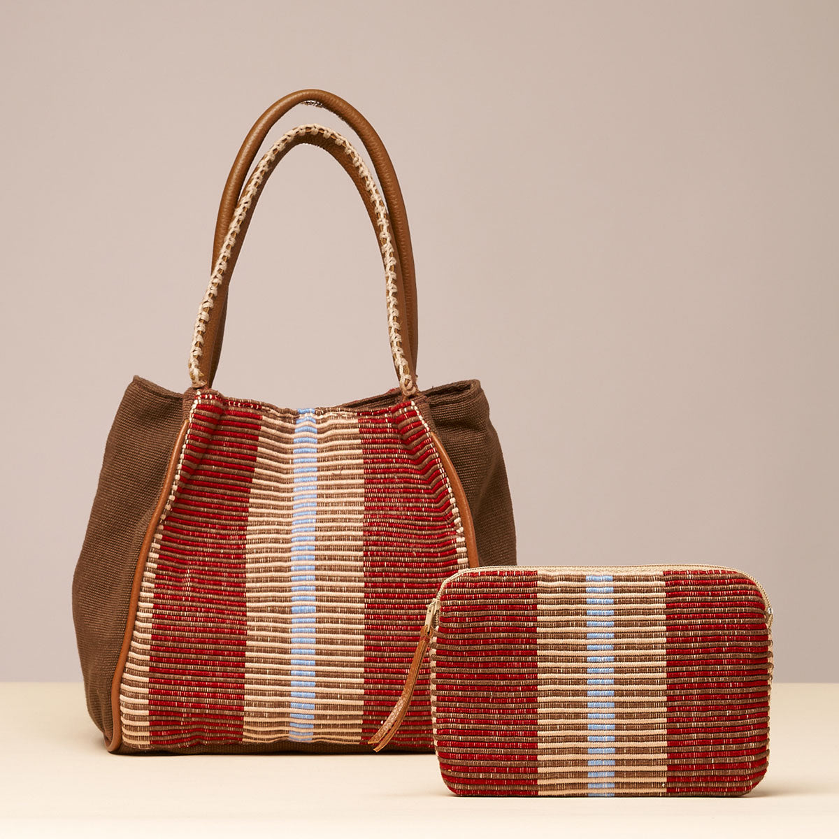 The hand woven artisan Teresa Wallet and Flora Petite Tote are placed together. Both have a Chestnut pattern, vertical burgundy and tan stripes.