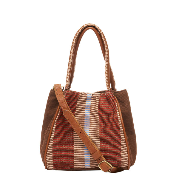 Hand woven artisan Flora Petite Tote in Chestnut shown at the front. The sides of the bag are in solid brown colors. The leather handles have white embroidered detailing. The Chestnut pattern has thick brown and tan stripes. A leather adjustable strap is hung diagonally.