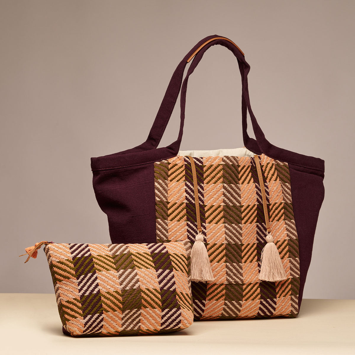 Artisan hand woven Rosa Tote and Cristina Cosmetic Pouch in Moss Weave are placed together. The Moss Weave is an olive green and orange plaid. The Rosa Tote has beige tassels with a leather cord. The Cristina Pouch has a leather zipper pull and a mini orange tassel.