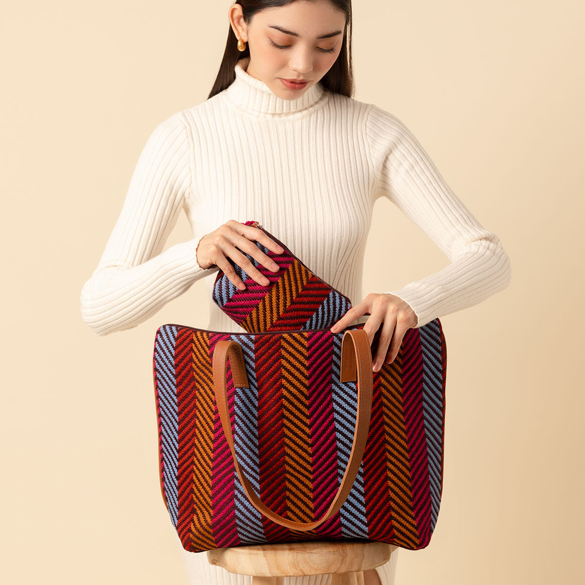 A model puts the Mini Cristina Pouch into the Estella Tote. Both are in the Winter Berry pattern.