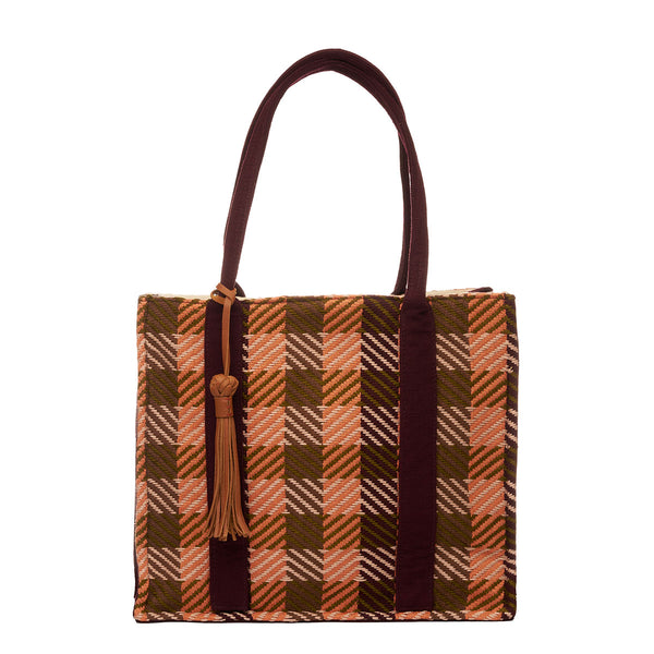 Hand woven artisan Irma Tote in Moss Weave pattern. The front of the bag is shown. The bag has a rectangular shape with an olive green and orange plaid pattern. It has a leather tassel attached to the dark brown handles.