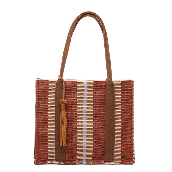 Hand woven artisan Irma Tote in Chestnut pattern. The front of the tote is shown. It has a rectangular shape with a leather tassel on the brown handles. The chestnut pattern has burgundy and tan vertical stripes.