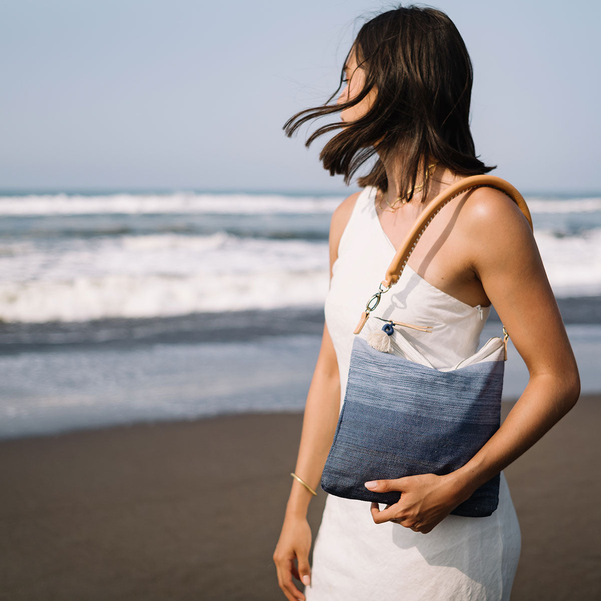 A model wears the unfolded Florentina Clutch-to-Hobo (Ocean Breeze) over her shoulder.