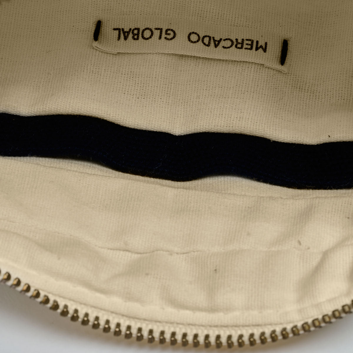 Interior view of the Felipa Belt Bag in Ocean Breeze. It has a beige lining with a dark blue hem for the pocket.