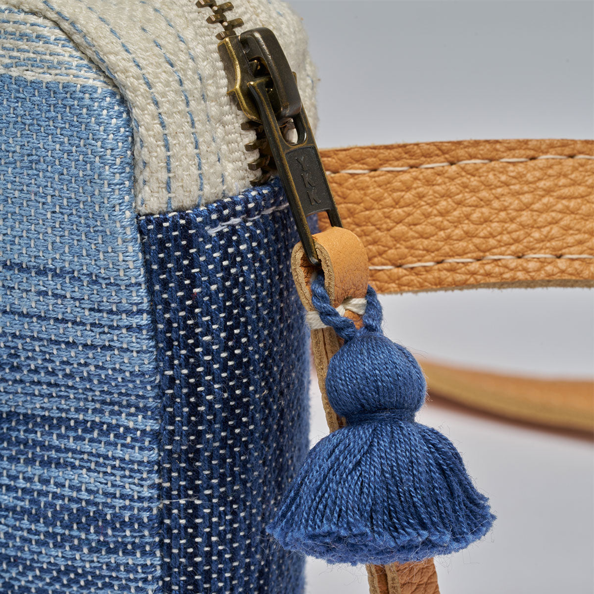 Felipa Belt Bag in Ocean Breeze. A close up of the zipper detail with leather pull and mini blue tassel.