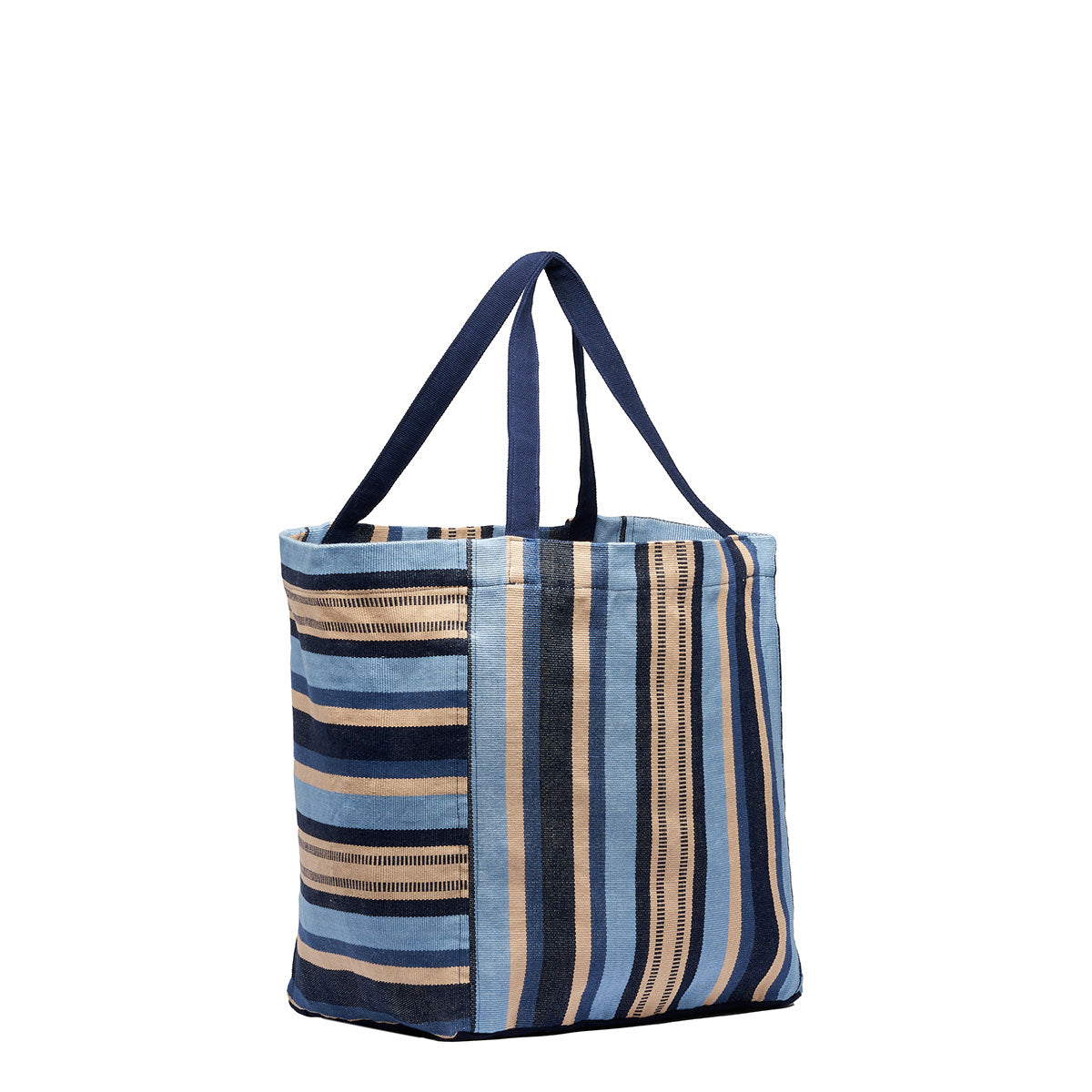 A side angle view of the Blanca Tote in Skyscape. The pattern has vertical and horizontal navy, beige, and light blue stripes. It has dark blue handles.