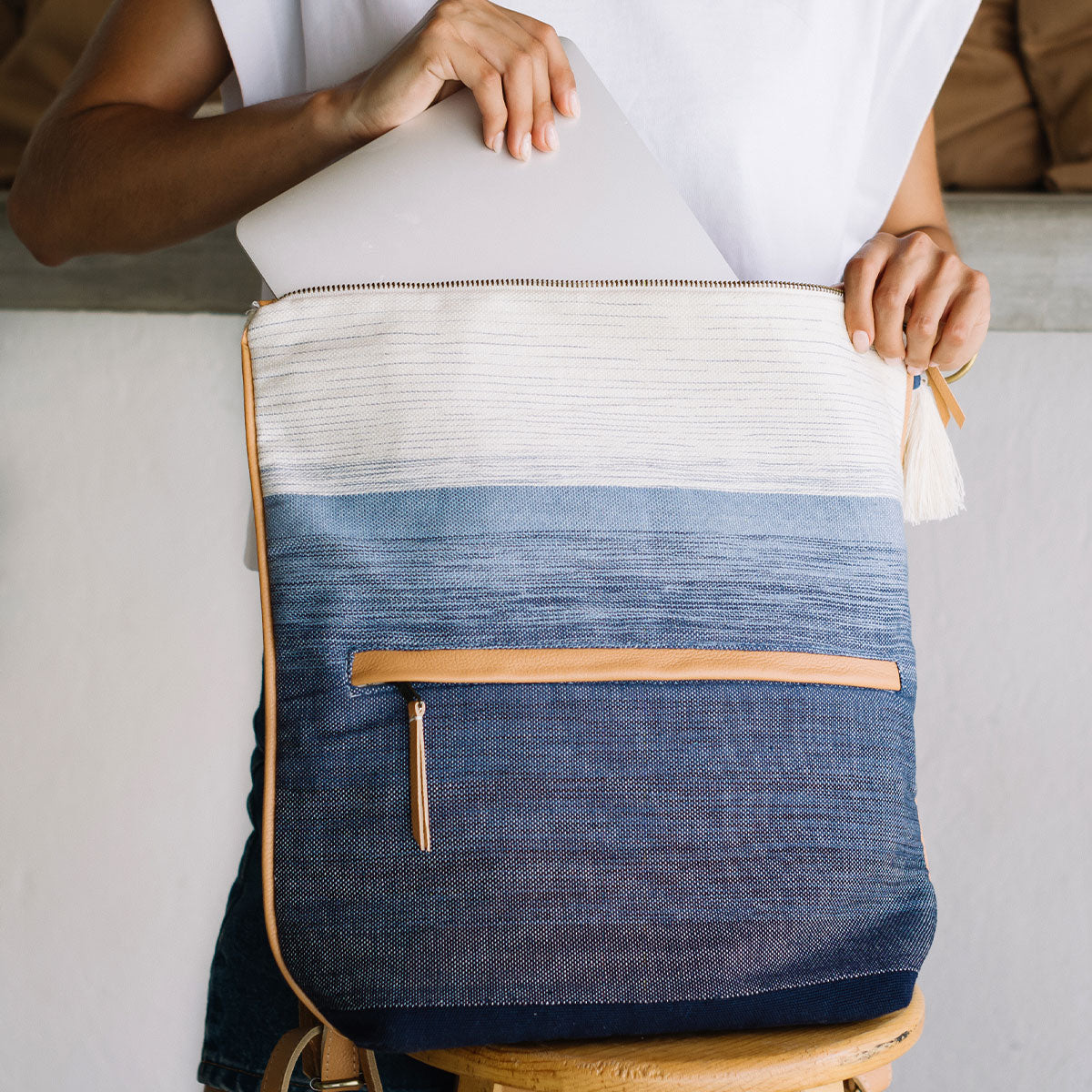 A model unzips the Lorena Backpack (Ocean Breeze) and puts a laptop inside.