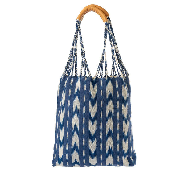 The front of the hand woven Apolonia Tote in Atitlán Hills pattern. This tote has woven cords attached to leather handles. It has vertical and chevron dark blue and white stripes.