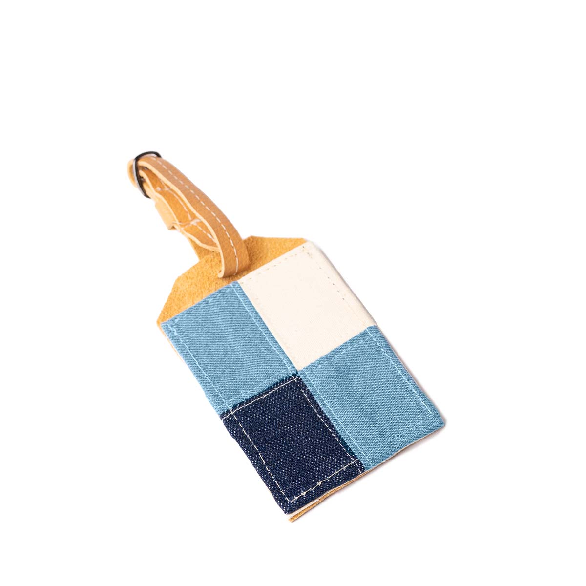 The back of the Ines Luggage Tag in 90s Denim. It has four squares, one in dark blue, two in light blue, and one in white. It has a leather adjustable strap.
